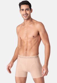 Béžové pánske boxerky vyrobené z hladkej tkaniny, s elastickým pásom s logom a kontúrovaným vreckom.