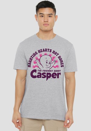 Young man wearing a gray t-shirt with a purple and pink Casper the Friendly Ghost graphic and the text "Haunting Hearts Not Homes."