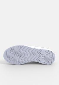 Semelle d'une basket blanche avec des motifs circulaires et en zigzag sur un fond uni clair.