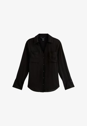 Chemise noire à manches longues en tissu lisse avec un col, fermeture à boutons, et deux poches poitrine. Elle présente des manches retroussées et un ourlet arrondi.