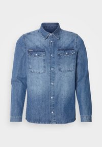 Chemise en jean bleu à manches longues avec col, fermeture boutonnée sur le devant, et deux poches poitrine à rabat avec boutons.