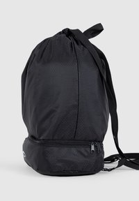 Black drawstring backpack with hexagonal texture, featuring a zippered bottom compartment and adjustable straps. Smooth, lightweight material.