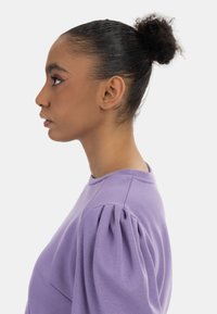 Lavendel sweatshirt med puffærmer og rund halsudskæring, lavet af en blød bomuldsblanding med en glat tekstur.