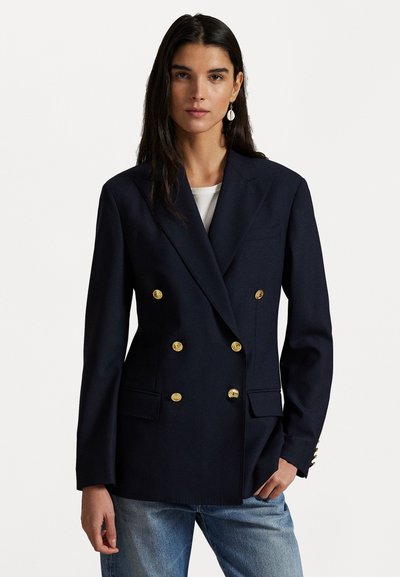 Merenneidon kaksirivinen bleiseri, joka on valmistettu teksturoidusta kankaasta. Siinä on kultaiset napit, kaksi etutaskua ja muotoiltu malli.