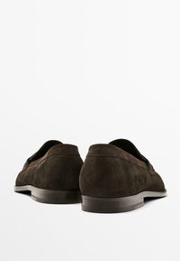 Brune ruskind loafers med en lav hæl, med en glat tekstur og et simpelt design. Bagsiden viser en subtil sømdetalje.
