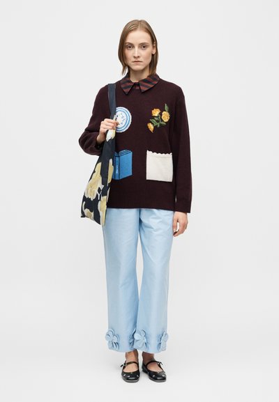 Burgundia toonitud kampsun lille- ja raamatuembleemidega, kombineeritud helesiniste pükstega, mis on kaunistatud lilledega. Mustad pehmed kingad ja mustriline kott.