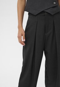 Upravené tmavosivé nohavice s prednými plisovaniami, vyrobené z pevnej látky, s vysokým pásom a bočnými vreckami.