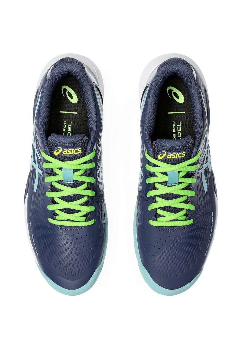Baskets de sport marine avec une tige texturée, des lacets verts et des accents bleu clair. Elles présentent un design en mesh et un talon renforcé.