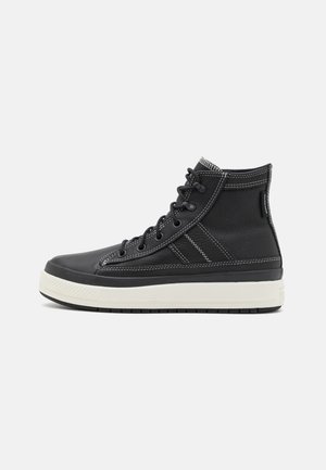 Sneaker înalt negru din piele texturată, cu o talpă din cauciuc alb, șireturi negre și cusături albe contrastante.
