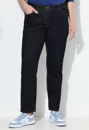 Dark blue denim jeans with visible stitching, front pockets, and a button closure. Paired with light blue athletic sneakers.