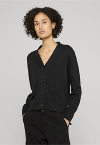 Čierny pletený kardigán s výstrihom do V, so šiestimi gombíkmi vpredu, rebrovanými manžetami a lemom. Ľahká textúra, voľný strih.