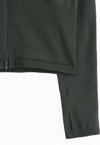 Dark green zip-up jacket with ribbed hem and sleeve cuff featuring thumb hole on right sleeve against white background.
