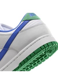 Vita sneakers med blå och gröna accenter, med en texturerad läderovandel, en grön mocka hälflik och en grön gummisula med ett mönstrat däck.