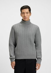 Grauer Rollkragenpullover mit Fischgrätmuster, geripptem Kragen und Bündchen, aus strukturiertem Strickmaterial. Lange Ärmel, lockere Passform.