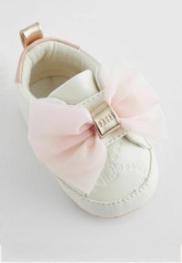 Witte leren babyschoen met een grote roze netten strik, gouden accent en gegraveerd ontwerp. Beschikt over een zachte binnenkant en een ronde neus.