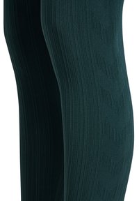 Gros plan sur des leggings en tissu côtelé vert foncé avec un motif en chevrons tricoté au niveau des cuisses.