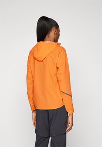 Oranje lichtgewicht jack met een capuchon, voorzien van reflecterende accenten en een relaxte pasvorm. Het heeft lange mouwen en een trekkoord bij de hals.