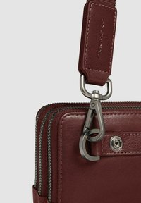 Bolso de cuero color marrón con un acabado texturizado, compartimentos de doble cremallera y un cierre de metal plateado para un cierre seguro.