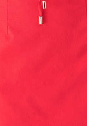 Rode stoffen rok met een gladde textuur, trekkoordsdetail en metalen accenten aan het uiteinde van het trekkoord.