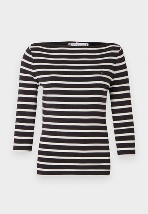 Černobílý pruhovaný top s dlouhým rukávem, lodičkovým výstřihem a malým logem. Vyroben z měkké látky, přiléhavý střih.