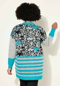 Cardigan lungo con un motivo floreale nero e grigio, dettagli turchesi e strisce orizzontali. Realizzato in morbido materiale a maglia.