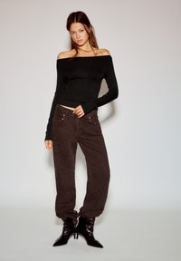 Czarna bluzka odsłaniająca ramiona, obcisłe rękawy, do tego brązowe spodnie w cętki lamparta z metalicznymi akcentami oraz czarne botki z ostro zakończonymi noskami.