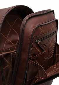 Mochila de cuero marrón con múltiples compartimentos, bolsillos con cremallera y un exterior texturizado. El interior tiene un forro con patrón de logotipos.