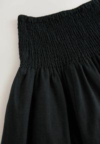 Robe noire avec un corsage froncé et une jupe plissée. Fabriquée en tissu léger avec une texture lisse. Sans motifs ni matériel visible.