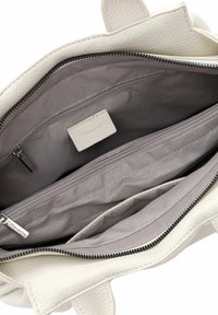Bolso tote de cuero blanco con un exterior texturizado. El interior incluye un forro de tela gris, un bolsillo con cremallera y dos bolsillos tipo deslizante.