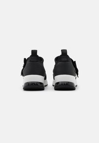 Schwarze Sportschuhe mit glattem Stoffobermaterial, weißer Zwischensohle und strukturiertem schwarzem Gummiaußensohle. Verfügen über flache Schnürsenkel und Zuglaschen hinten.