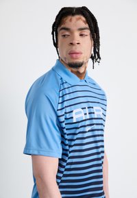 Collared polo shirt in light blue with navy horizontal stripes and white "AIR" logo. Made from breathable material with short sleeves.