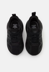 Svarta sportskor med övre del i mesh, markanta ränder, snörningssystem, vadderad sula och dragflik vid hälen. Adidas-logotyp synlig på tungan.