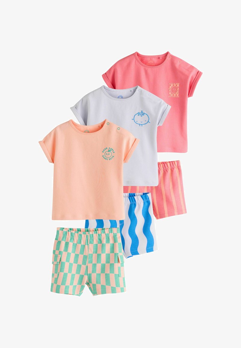 Tre completi di magliette a maniche corte e pantaloncini per bambini in pesca pastello, bianco e corallo con motivi giocosi di frutta e righe o quadretti.