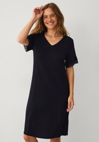 Czarna sukienka z dekoltem w serek i krótkimi rękawami, z koronkowymi akcentami na brzegach rękawów. Miękka tkanina o luźnym kroju, sięgająca do połowy łydki.
