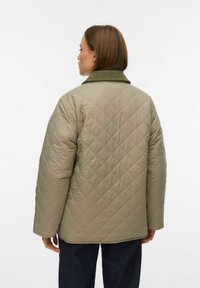 Veste matelassée surdimensionnée en vert olive clair, avec un col contrastant, une texture côtelée et une coupe décontractée.