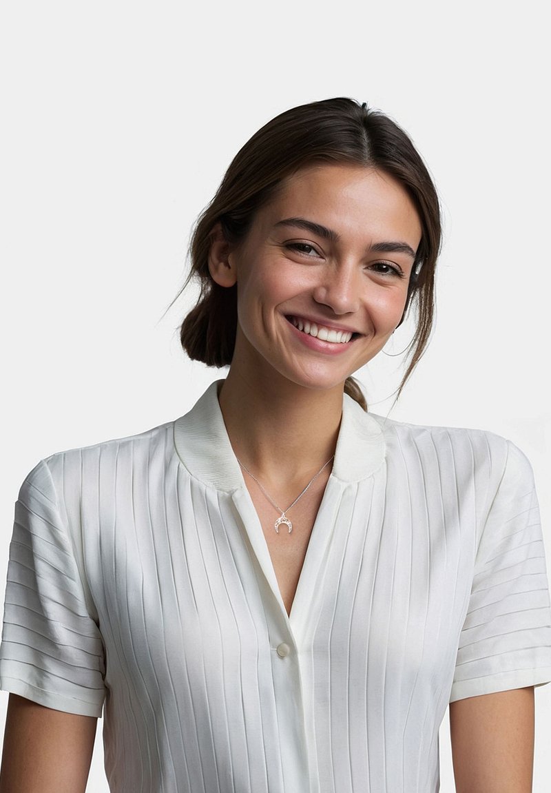 Hvid skjorte med krave og lodrette striber, med korte ærmer. En sølv halskæde med en halvmåne vedhæng er synlig på halsen.