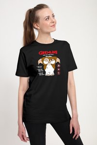 Sort T-shirt med Gremlins-grafik, der viser en tegneseriefigur og tekst, der angiver tre regler. Kortærmet, rund hals.