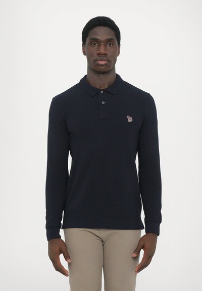 Polo à manches longues navy avec col et deux boutons, comportant un petit logo brodé sur la poitrine gauche et des poignets côtelés.