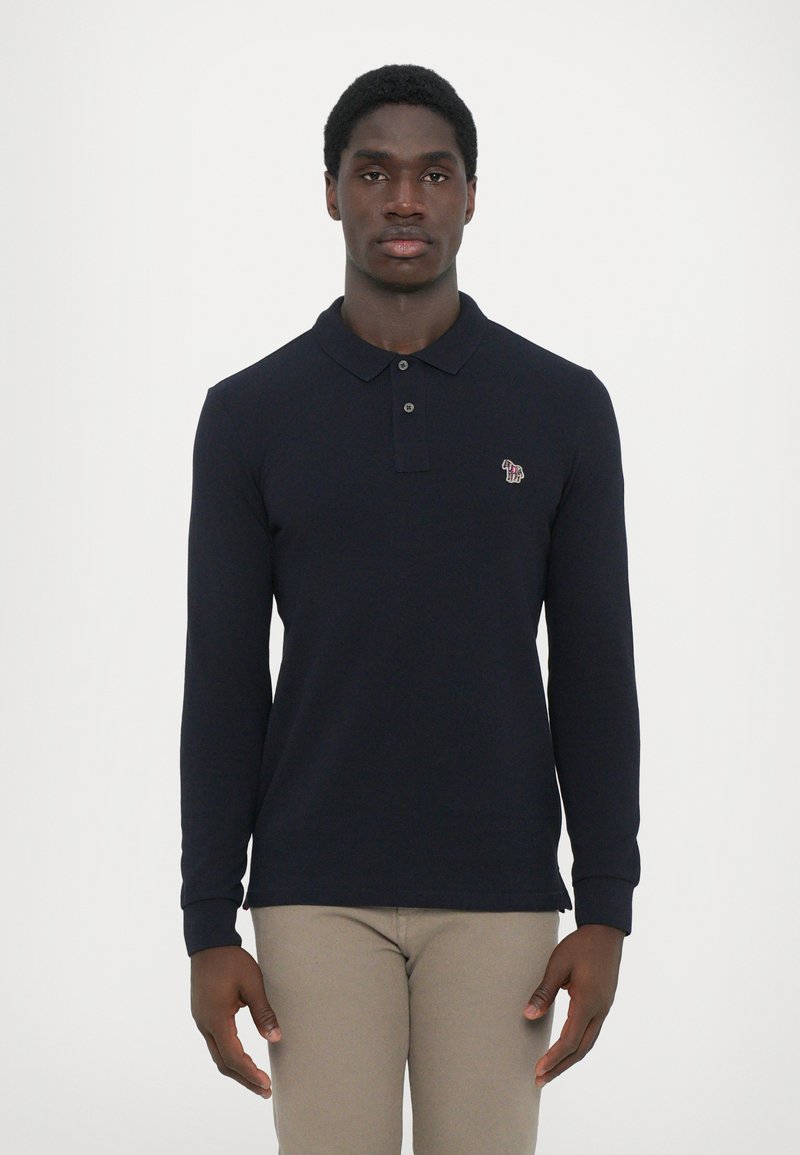 Polo de manga longa azul-marinho com colarinho e dois botões, apresentando um pequeno logo bordado no lado esquerdo do peito e punhos canelados.