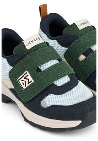 Sneakers verdi e blu navy con pannelli in rete, cinturini in Velcro e una sovrapposizione verde testurizzata. Presentano una suola beige e un dettaglio del logo a contrasto.
