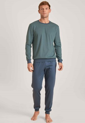 Dunkelblauses Langarmshirt mit geometrischem Muster und geripptem Halsausschnitt, kombiniert mit passenden blauen, schmal zulaufenden Jogginghosen aus glattem Stoff.