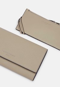 Beżowy skórzany portfel o teksturowanym wykończeniu, z designem składanym i subtelnym tłoczonym logo. W zestawie znajduje się pasujący portfel na karty.