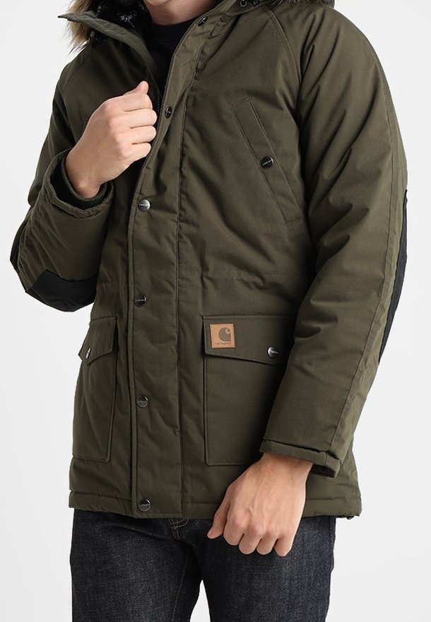 Olivově zelená zateplená bunda s černou podšívkou, s kapucí lemovanou kožešinou, několika kapsami a čtvercovou nášivkou loga na přední straně.