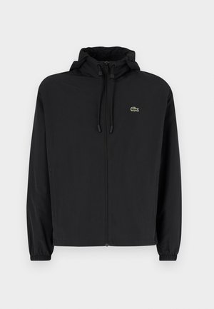 Black zip-up jacket with a hood, made of lightweight material. Features elastic cuffs and a small green logo on the left chest.
