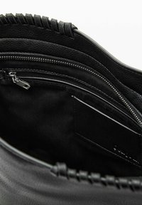 Geantă de mână din piele neagră cu finisaj texturat, compartimente cu fermoar și un design împletit în partea superioară. Interiorul este căptușit cu o țesătură netedă și are un buzunar pentru carduri.