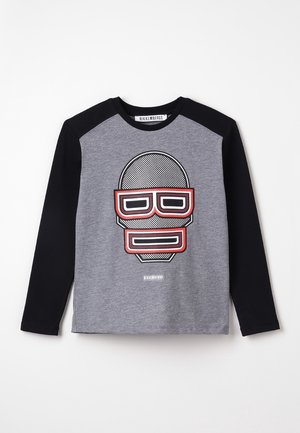 Langärmliges Hemd mit schwarzen Ärmeln und grauem Körper, das auf der Vorderseite ein großes stilisiertes Gesicht in Schwarz, Weiß und Rot zeigt.