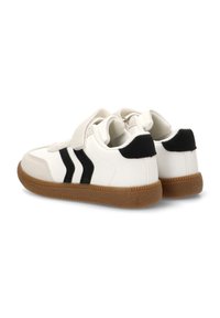 Zapatillas blancas con rayas negras, hechas de material sintético suave. Suela de goma texturizada. Cierres de tira de velcro, cuello acolchado.