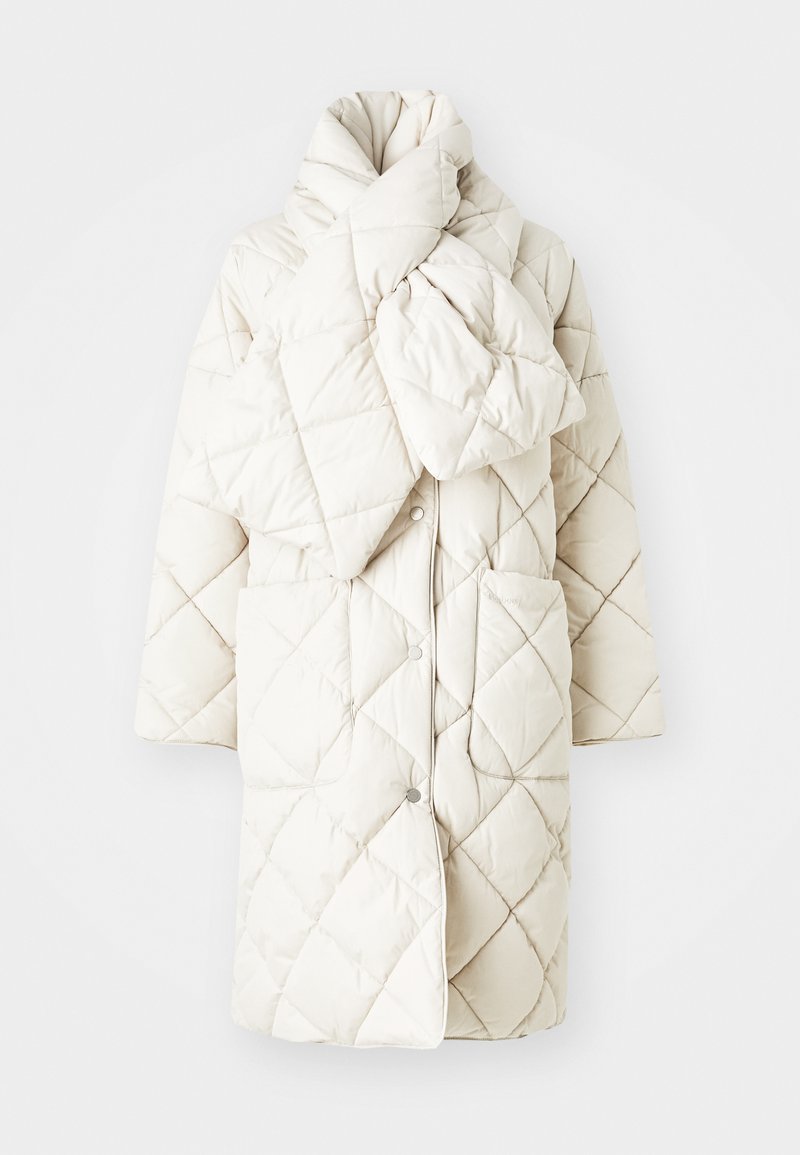 Gepolsterter Steppmantel in sanftem Cremeton, mit hohem Kragen, zwei Fronttaschen und Knöpfen. Leichtgewicht, glatte Textur mit geometrischem Muster.