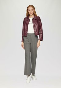 Veste en cuir bordeaux, tee-shirt blanc avec imprimé, pantalon gris ajusté, sneakers blancs. Texture lisse, design ajusté et style de veste courte.