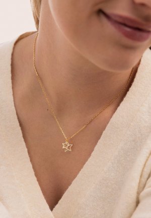 Cadena de oro con colgante en forma de estrella adornada con circonitas transparentes. La estrella tiene una superficie texturizada y un acabado pulido.
